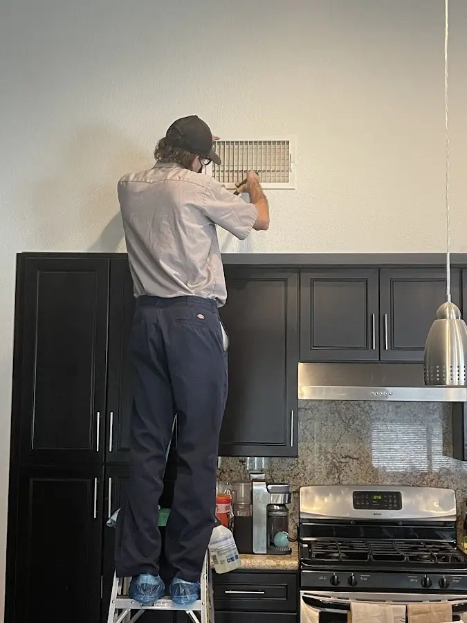 Technician inspecting an air vent during HVAC service in Temple City